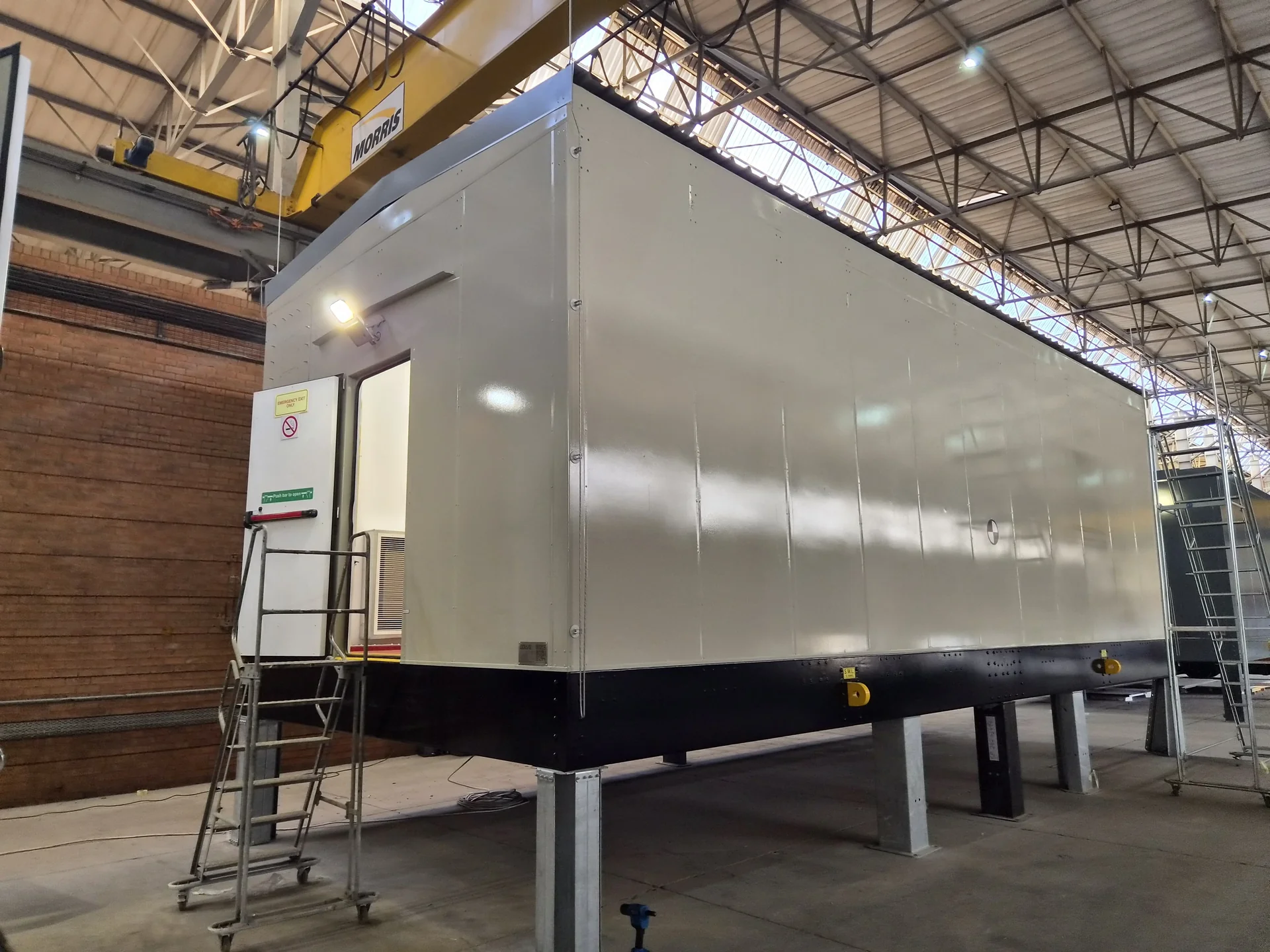Factory floor with workers applying industrial coating to large equipment surfaces